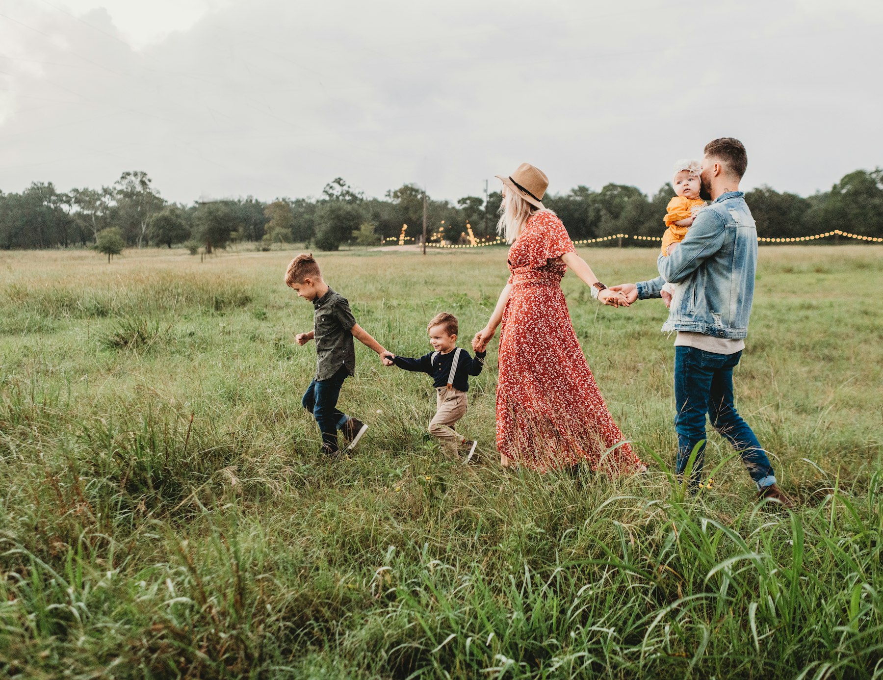 A young family walking hand in hand through a summer meadow