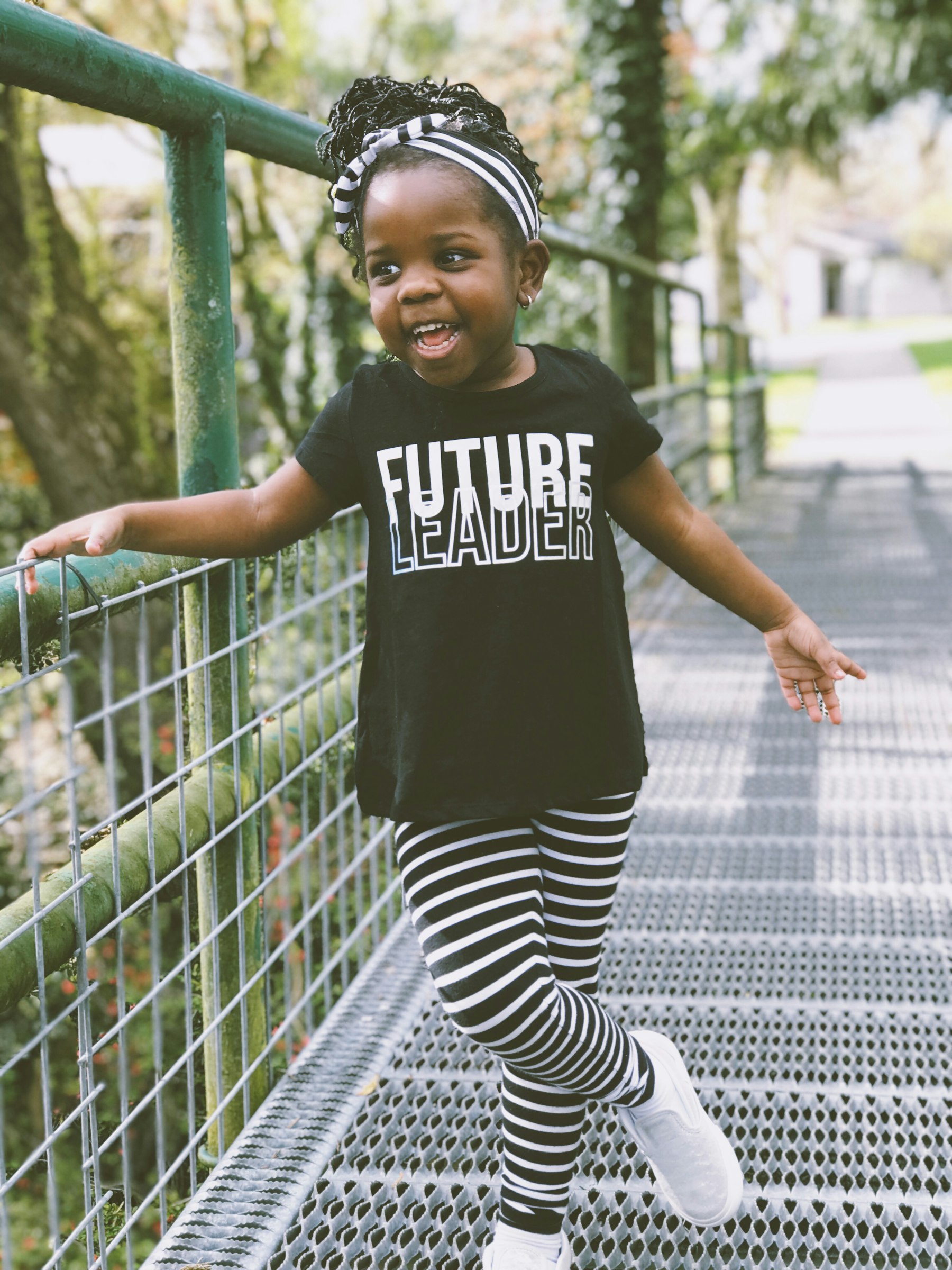 A little girl laughing as she crosses a footbridge in the park