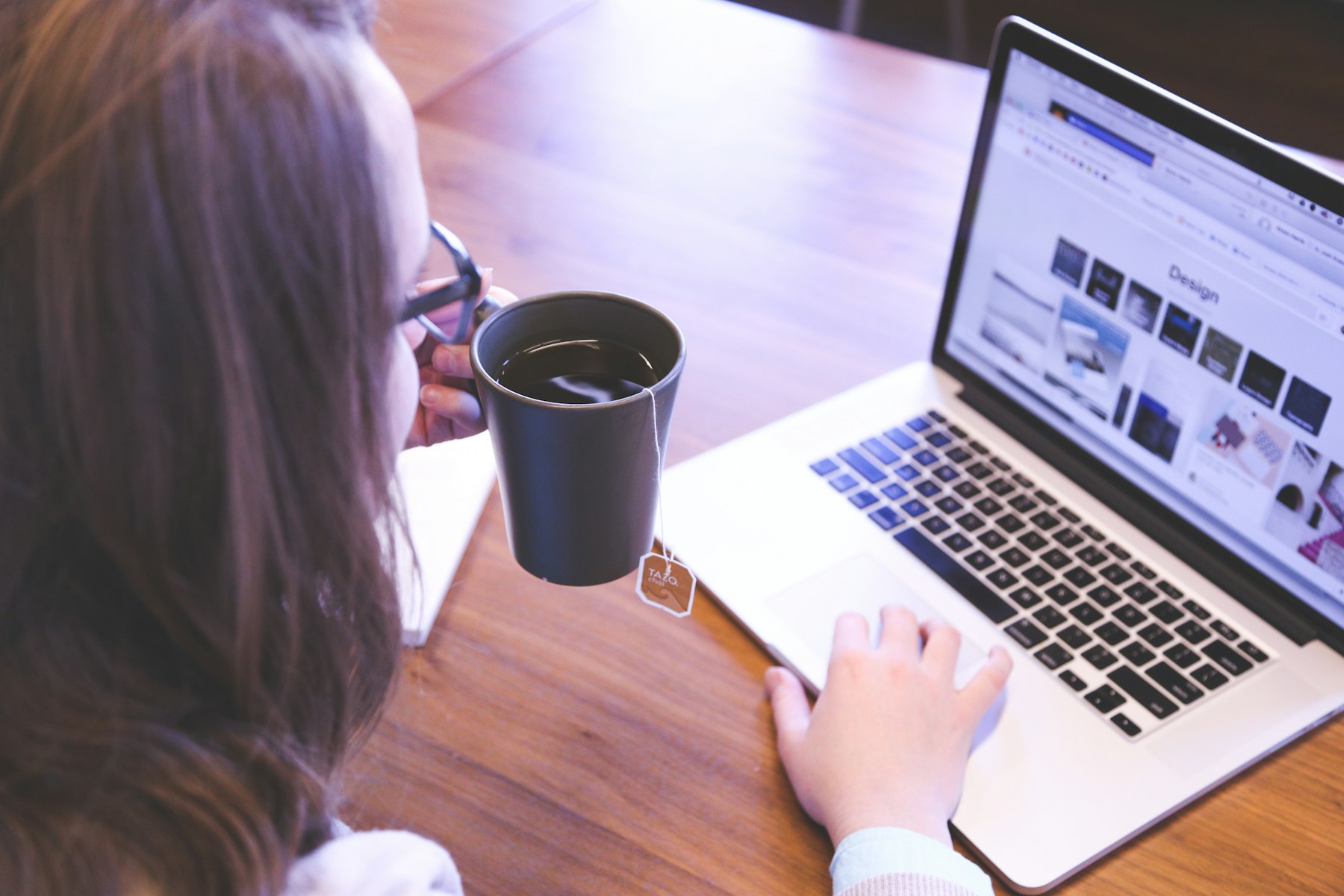 A woman at her kitchen table with a cup of tea, filling in an application on her laptop